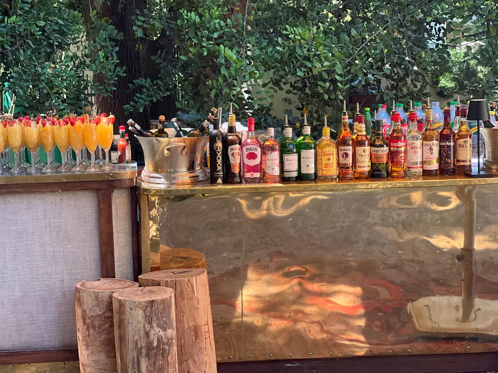 A hammered brass bar with tree-stump stools, a line of spirits and mimosas topped with strawberries