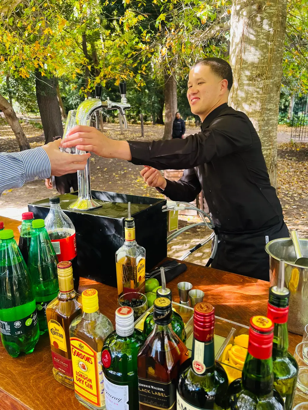A bartender handing a glass across a chrome twin-tap tower